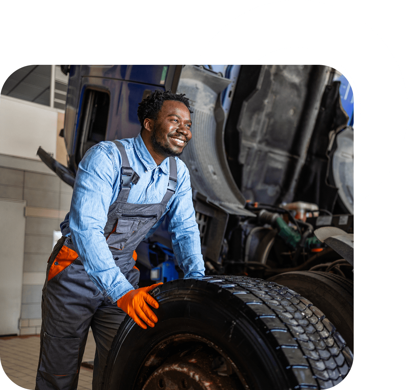 Man in overalls with truck tire